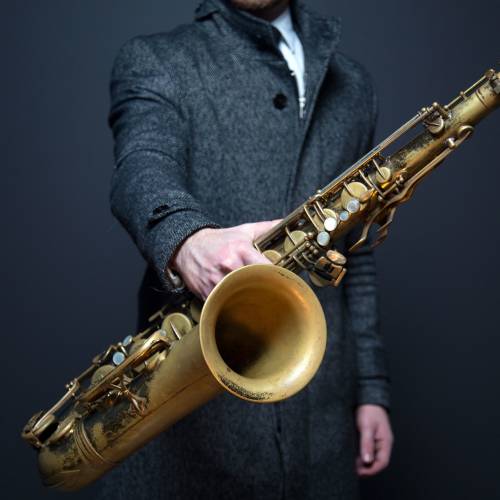 Mężczyzna trzymający saksofon w jednej ręce