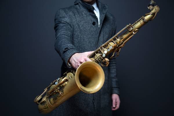 Mężczyzna trzymający saksofon w jednej ręce